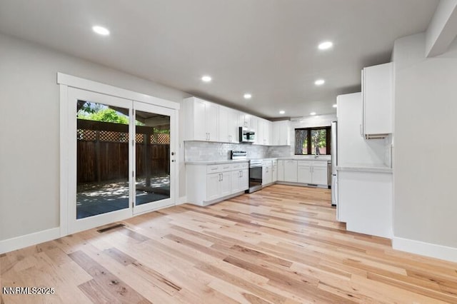 2080 Del Rio Ln, Reno, NV 89509 - kitchen featuring appliances with stainless steel finishes, light countertops, light wood-type flooring, white cabinetry, and decorative backsplash