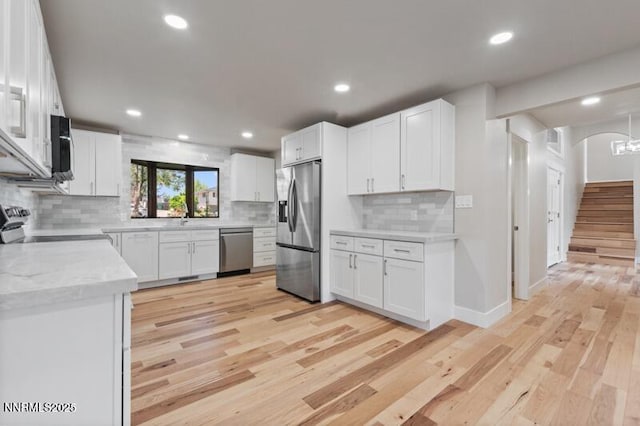 2080 Del Rio Ln, Reno, NV 89509 - kitchen featuring appliances with stainless steel finishes, backsplash, light wood-type flooring, white cabinets, and recessed lighting