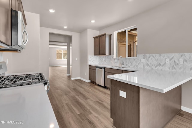 1466 Copper Point Cir, Reno, NV 89519 - kitchen featuring appliances with stainless steel finishes, a sink, a peninsula, decorative backsplash, and light wood-type flooring