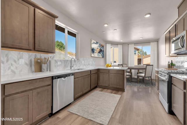 1466 Copper Point Cir, Reno, NV 89519 - kitchen with appliances with stainless steel finishes, a sink, a peninsula, light wood finished floors, and backsplash