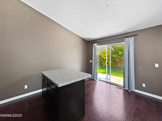 620 W National Ave, Winnemucca, NV 89445 - interior space with dark wood-type flooring, baseboards, a textured ceiling, a kitchen island, and dark cabinets