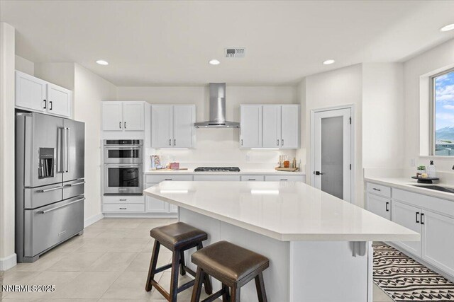 11235 Freedom Range Ln, Reno, NV 89521 - kitchen with appliances with stainless steel finishes, wall chimney range hood, a breakfast bar, white cabinets, and light countertops