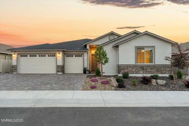 11235 Freedom Range Ln, Reno, NV 89521 - view of front of house featuring stone siding, a garage, stucco siding, and decorative driveway