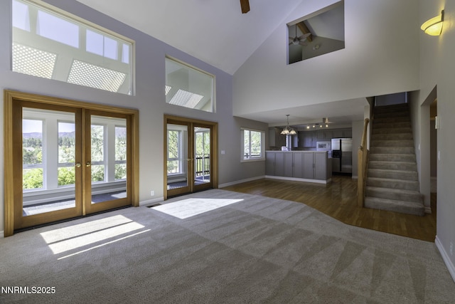 16360 Jefte Ct, Reno, NV 89511 - unfurnished living room featuring dark colored carpet, french doors, high vaulted ceiling, a chandelier, and stairway