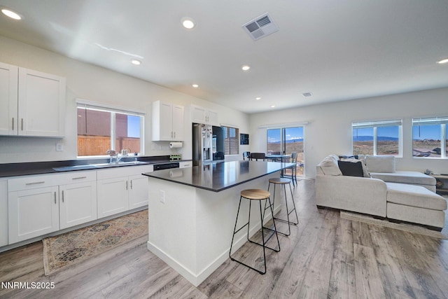 2040 Painted Sky Way, Sun Valley, NV 89433 - kitchen with stainless steel refrigerator with ice dispenser, open floor plan, dark countertops, a breakfast bar area, and white cabinets