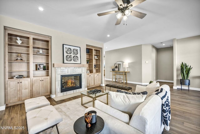 3952 Siena Dr, Carson City, NV 89703 - living area featuring baseboards, wood finished floors, a tiled fireplace, vaulted ceiling, and a ceiling fan