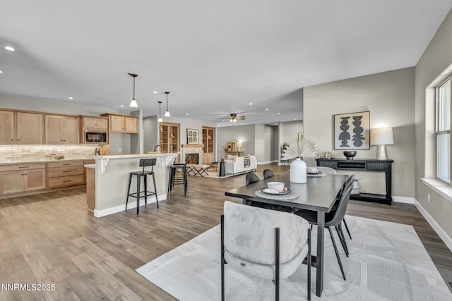 3952 Siena Dr, Carson City, NV 89703 - dining area featuring recessed lighting, light wood finished floors, a ceiling fan, baseboards, and a lit fireplace
