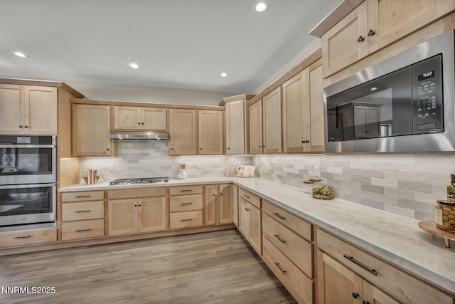 3952 Siena Dr, Carson City, NV 89703 - kitchen with stainless steel appliances, light brown cabinets, under cabinet range hood, tasteful backsplash, and light countertops
