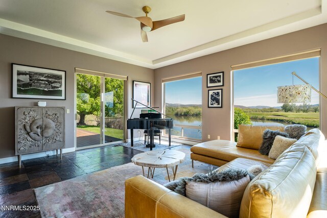 2473 Genoa Aspen Dr, Genoa, NV 89411 - living area featuring stone tile flooring, a water view, a ceiling fan, and baseboards