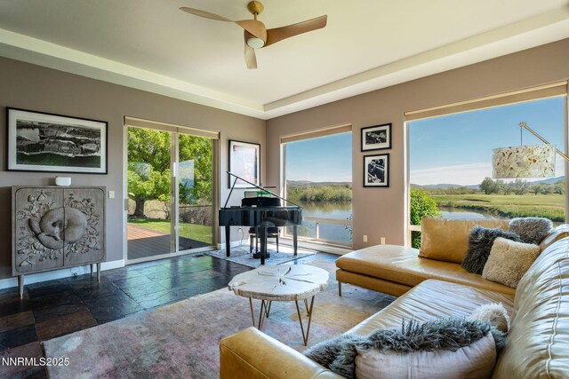 2473 Genoa Aspen Dr, Genoa, NV 89411 - living area with stone tile flooring, a ceiling fan, a water view, and baseboards