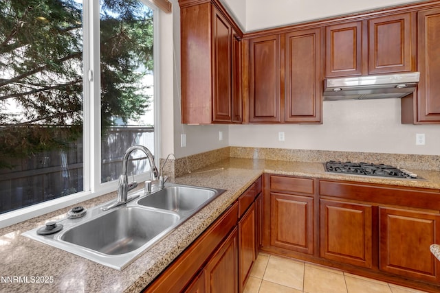 8355 Opal Ranch Way, Reno, NV 89506 - kitchen with a sink, under cabinet range hood, stainless steel gas stovetop, brown cabinetry, and light tile patterned floors
