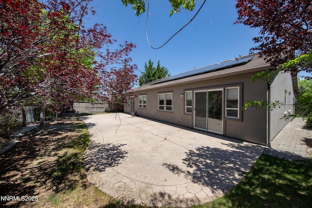 8355 Opal Ranch Way, Reno, NV 89506 - back of property with stucco siding, roof mounted solar panels, a fenced backyard, and a patio