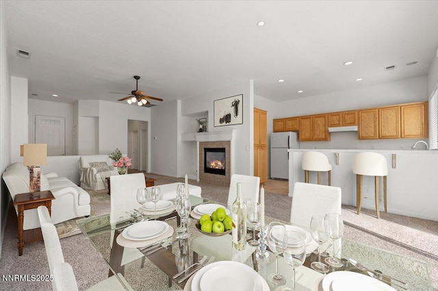 10548 Bliss Ct, Reno, NV 89521 - dining space featuring a tiled fireplace, light colored carpet, a ceiling fan, and recessed lighting