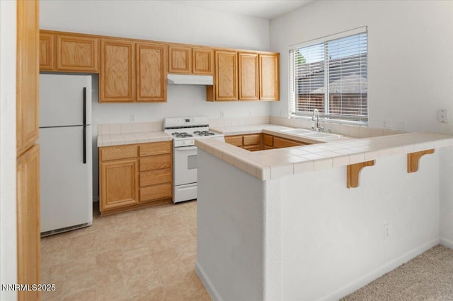 10548 Bliss Ct, Reno, NV 89521 - kitchen with white appliances, a sink, a peninsula, tile counters, and under cabinet range hood