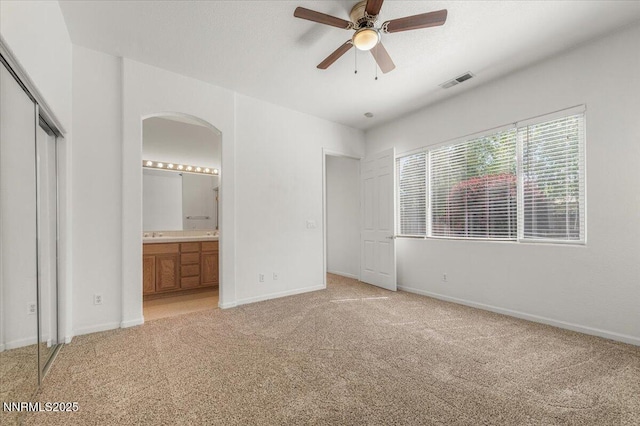 10548 Bliss Ct, Reno, NV 89521 - unfurnished bedroom featuring arched walkways, light colored carpet, baseboards, and connected bathroom