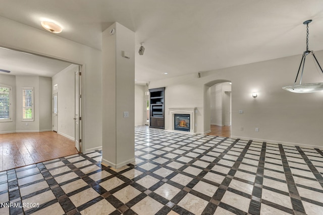 9900 Wilbur May Pkwy Apt 2801, Reno, NV 89521 - unfurnished living room with inlaid floor details, baseboards, arched walkways, and a glass covered fireplace