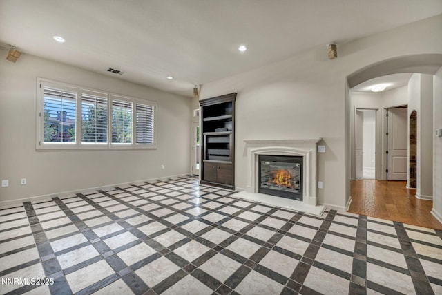 9900 Wilbur May Pkwy Apt 2801, Reno, NV 89521 - unfurnished living room featuring inlaid floor details, baseboards, recessed lighting, arched walkways, and a glass covered fireplace