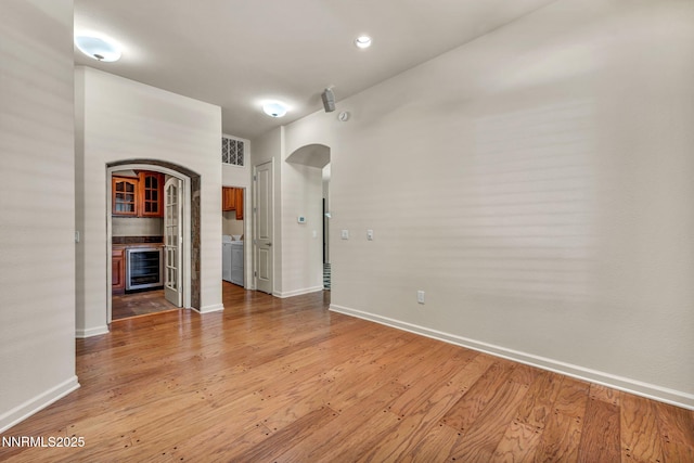 9900 Wilbur May Pkwy Apt 2801, Reno, NV 89521 - empty room featuring wine cooler, arched walkways, baseboards, and light wood-style floors
