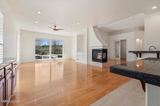 2728 Spirit Rock Trl, Reno, NV 89511 - unfurnished living room with a multi sided fireplace, a ceiling fan, recessed lighting, light wood-type flooring, and baseboards