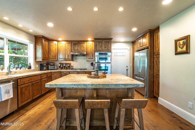 625 Freel Dr, Zephyr Cove, NV 89448 - kitchen featuring appliances with stainless steel finishes, a kitchen island, under cabinet range hood, recessed lighting, and a breakfast bar