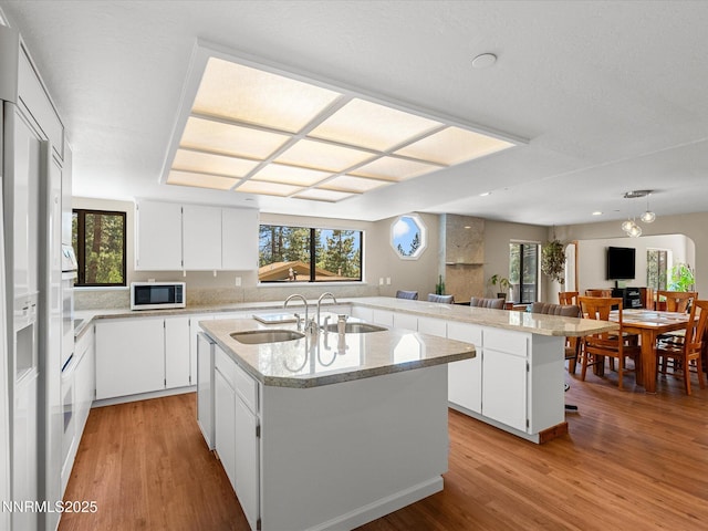315 Paiute Dr, Zephyr Cove, NV 89448 - kitchen featuring white appliances, light wood-style flooring, a center island with sink, white cabinetry, and healthy amount of natural light