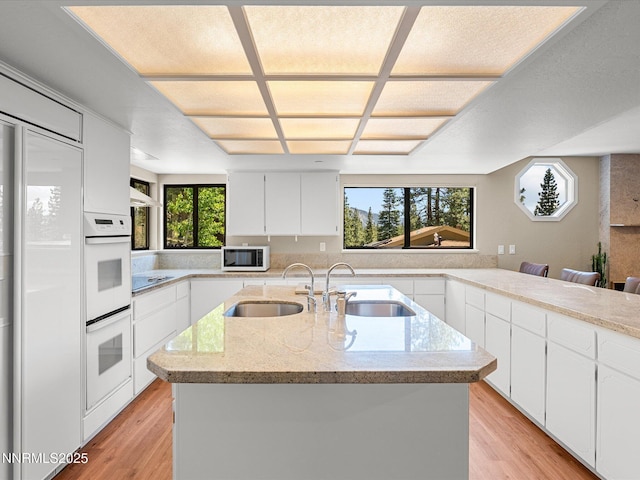 315 Paiute Dr, Zephyr Cove, NV 89448 - kitchen with white appliances, light wood finished floors, a kitchen island with sink, and white cabinets
