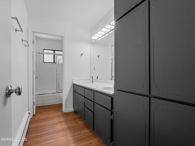 315 Paiute Dr, Zephyr Cove, NV 89448 - bathroom featuring baseboard heating, wood finished floors, double vanity, and enclosed tub / shower combo