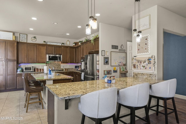 11760 Valley Crest Dr, Sparks, NV 89441 - kitchen with stainless steel appliances, a peninsula, recessed lighting, a kitchen bar, and light stone counters