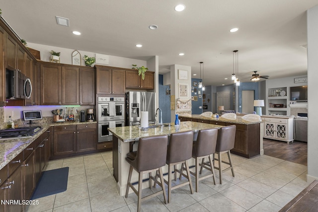 11760 Valley Crest Dr, Sparks, NV 89441 - kitchen featuring stainless steel appliances, a ceiling fan, a sink, light stone countertops, and light tile patterned floors