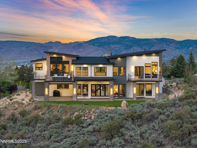 3041 Palmer Pointe Ct, Reno, NV 89511 - back of property at dusk with a balcony, stucco siding, a mountain view, and a patio