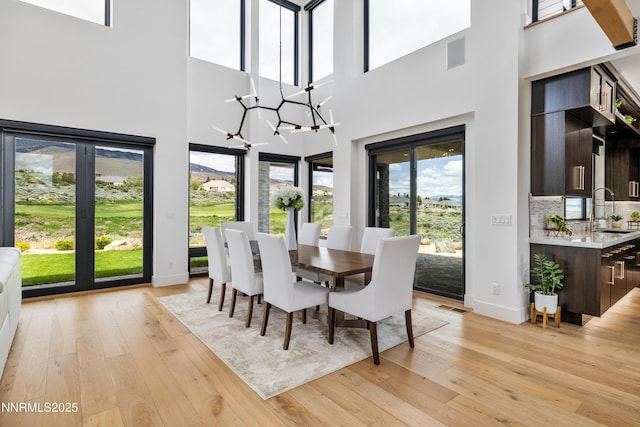 3041 Palmer Pointe Ct, Reno, NV 89511 - dining space featuring baseboards, light wood finished floors, a chandelier, and a towering ceiling