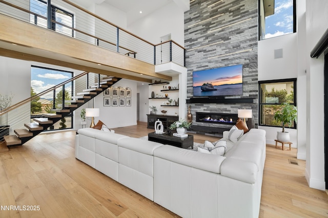 3041 Palmer Pointe Ct, Reno, NV 89511 - living area featuring a high ceiling, stairs, a fireplace, light wood-style flooring, and plenty of natural light