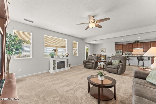 2269 Isabella Ct, Sparks, NV 89434 - living room featuring ceiling fan, a glass covered fireplace, light carpet, baseboards, and a textured ceiling