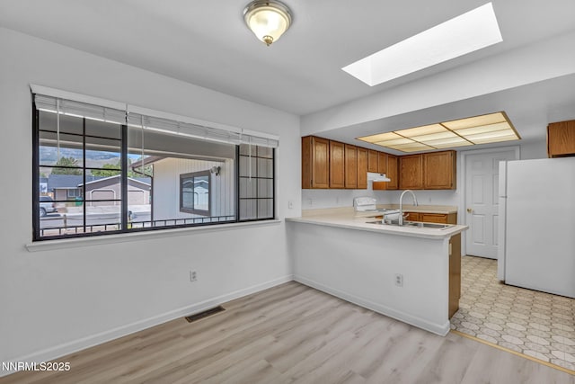 3803 Imperial Way, Carson City, NV 89706 - kitchen featuring white appliances, a skylight, a peninsula, brown cabinets, and light countertops