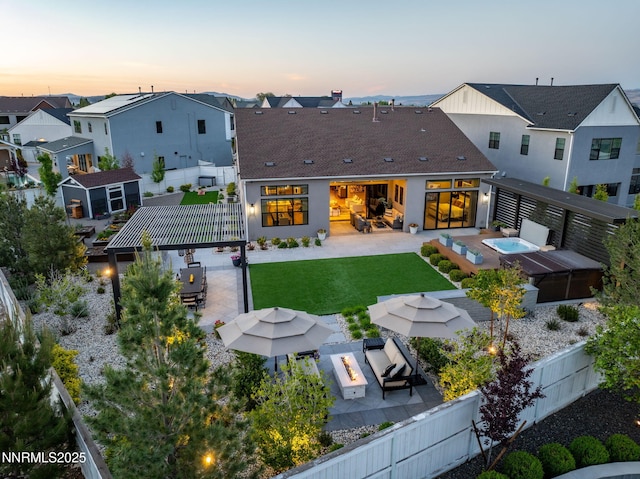 208 Criollo Ct, Reno, NV 89511 - back of property at dusk with a patio area, an outdoor living space with a fire pit, a shingled roof, and a residential view