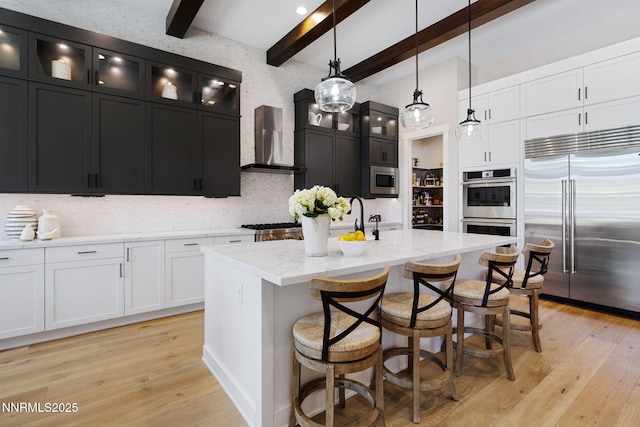 208 Criollo Ct, Reno, NV 89511 - kitchen with built in appliances, wall chimney exhaust hood, dark cabinetry, decorative backsplash, and light wood-style floors