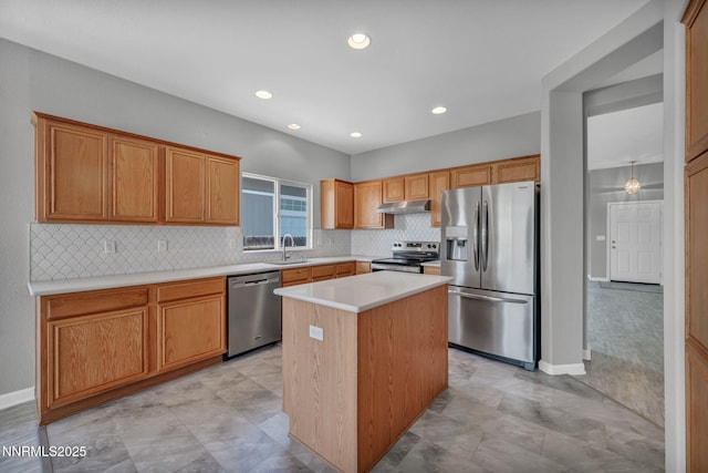 9951 Grand Falls Dr, Reno, NV 89506 - kitchen with stainless steel appliances, under cabinet range hood, decorative backsplash, light countertops, and a kitchen island