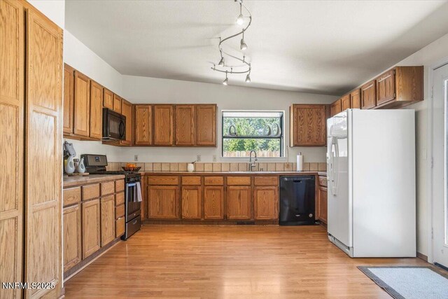 806 Bluerock Rd, Gardnerville, NV 89460 - kitchen with black appliances, a sink, brown cabinets, vaulted ceiling, and light wood-style floors