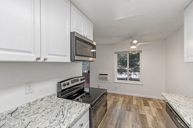 4608 Neil Rd Unit 226, Reno, NV 89502 - kitchen featuring appliances with stainless steel finishes, light wood finished floors, white cabinets, ceiling fan, and a wall mounted air conditioner