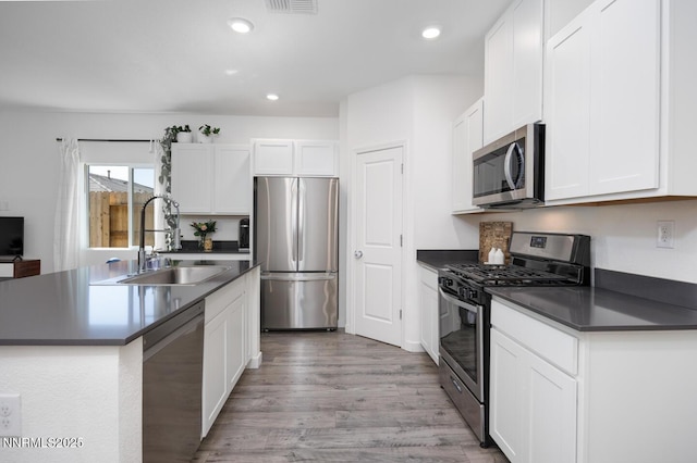 703 Sycamore Dr, Fallon, NV 89406 - kitchen featuring appliances with stainless steel finishes, a sink, dark countertops, light wood-type flooring, and white cabinetry