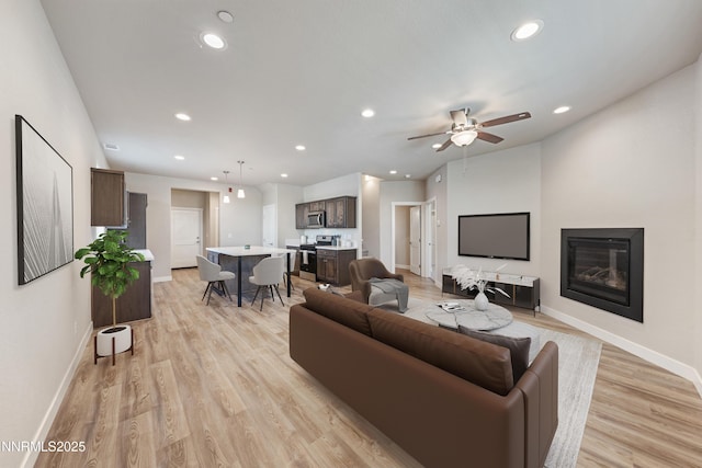 1170 Montevideo Cir, Minden, NV 89423 - living area featuring recessed lighting, baseboards, light wood-type flooring, a ceiling fan, and a glass covered fireplace