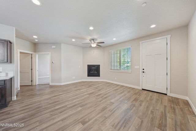 1170 Montevideo Cir, Minden, NV 89423 - unfurnished living room with ceiling fan, recessed lighting, a glass covered fireplace, light wood finished floors, and baseboards