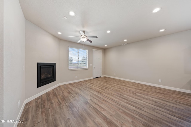 1170 Montevideo Cir, Minden, NV 89423 - unfurnished living room with a ceiling fan, wood finished floors, recessed lighting, a glass covered fireplace, and baseboards