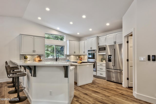 997 Dorcey Dr, Incline Village, NV 89451 - kitchen featuring appliances with stainless steel finishes, a kitchen bar, a peninsula, tasteful backsplash, and lofted ceiling