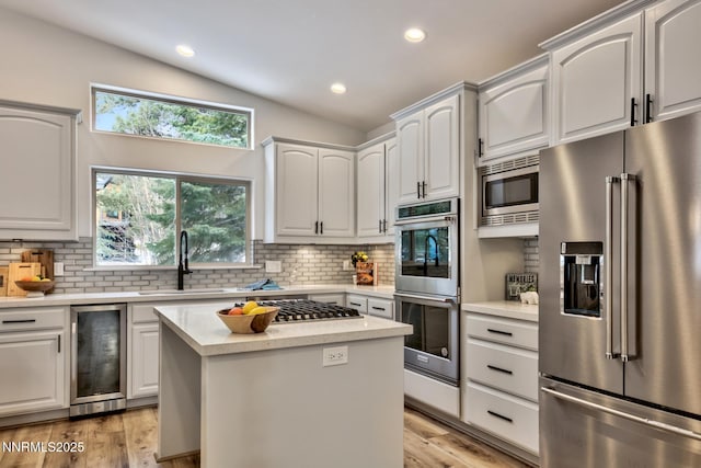 997 Dorcey Dr, Incline Village, NV 89451 - kitchen with appliances with stainless steel finishes, beverage cooler, vaulted ceiling, backsplash, and light wood-style floors
