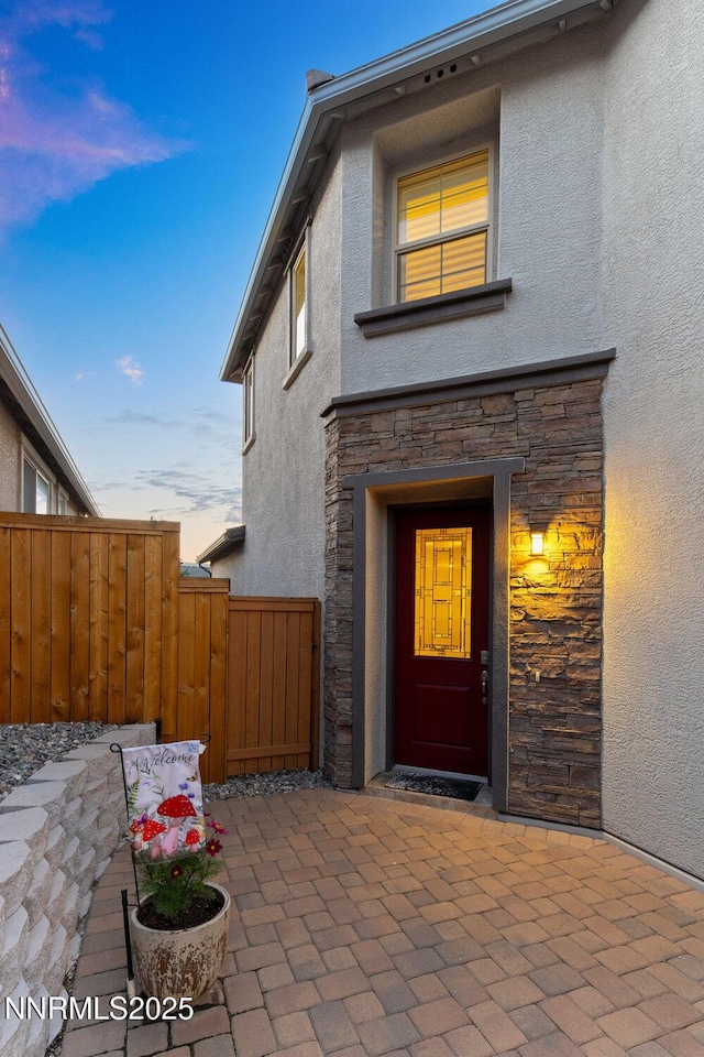 1385 Balfour Dr, Reno, NV 89509 - exterior entry at dusk featuring stucco siding, stone siding, and a patio area