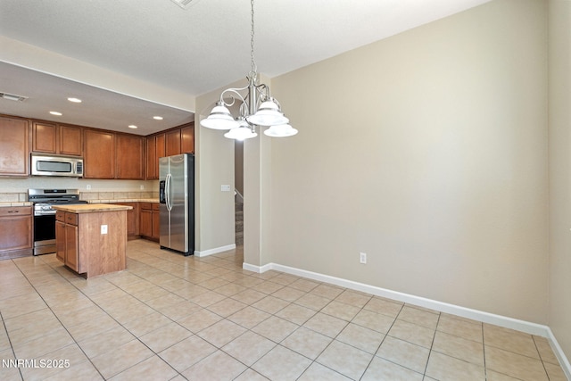 7121 Jermann Dr, Sparks, NV 89436 - kitchen with appliances with stainless steel finishes, a center island, a chandelier, recessed lighting, and light tile patterned floors