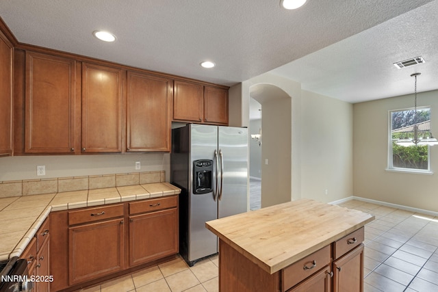 7121 Jermann Dr, Sparks, NV 89436 - kitchen with stainless steel refrigerator with ice dispenser, light tile patterned flooring, butcher block countertops, a textured ceiling, and brown cabinetry