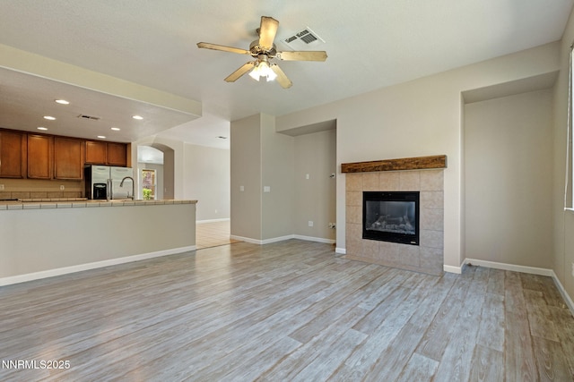 7121 Jermann Dr, Sparks, NV 89436 - unfurnished living room with a ceiling fan, light wood-style floors, recessed lighting, a fireplace, and arched walkways