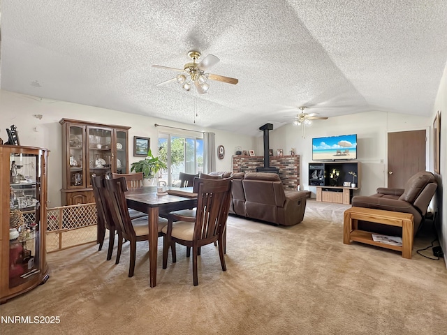 1331 Stephanie Way, Minden, NV 89423 - dining space featuring a wood stove, a ceiling fan, light carpet, a textured ceiling, and vaulted ceiling